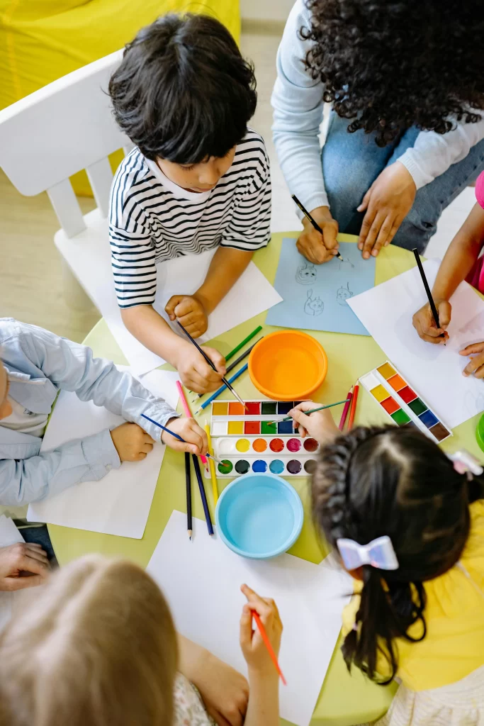 Photograph by Yankrukov shows Kids top view coloring with watercolors in a classroom - ANIMaD